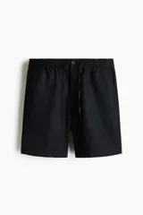 Short negro de corte regular fit, confeccionado en mezcla liviana de lino y algodón. Posee cintura elástica con cordón de ajuste, bragueta con botón, bolsillos en las costuras laterales y un bolsillo ojal en la parte posterior.