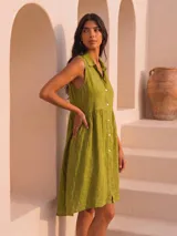 Vestido camisero midi sin mangas de lino italiano, color verde, con cuello camisero, cierre frontal de botones y diseño con corte en la cintura y falda ligeramente fruncida.