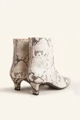 Botín blanco con estampado de piel de serpiente, punta fina y taco chupete. Cierre con cremallera en la parte trasera.