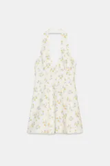 Vestido corto blanco con estampado floral en tonos amarillo y azul. Diseño con cuello halter, escote pronunciado en pico y cierre frontal de botones.