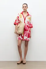 Túnica de corte recto y suelto con estampa floral en tonos de rosado, rojo y amarillo, cuello camisero rojo y mangas cortas holgadas.