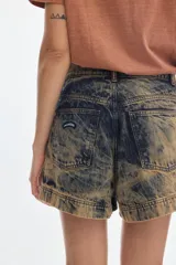 Short de denim tiro alto y corte relajado, con efecto de lavado desgastado en tonos amarillos y oscuros, pierna ancha y costuras en la parte delantera.