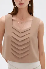 Musculosa sin mangas de color natural con cuello cuadrado y detalles de pliegues frontales en forma de chevrón.