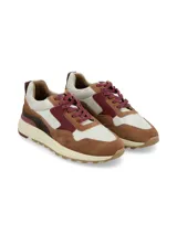 Sneaker deportivo de cueros combinados en tonos marrón, bordó, beige y detalles plateados texturados, con cordones y suela chunky de goma.