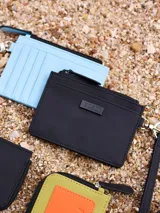 Billetera de poliuretano color celeste, con cierre de cremallera y correa de mano.