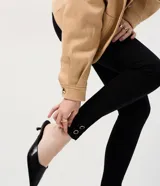 Pantalón de jean modelo skinny con cintura alta, cierre frontal con botón y cremallera, bolsillos funcionales y detalle metálico aplicado en el bajo cerca del tobillo.