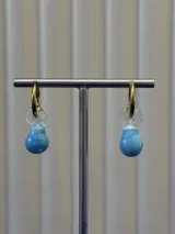 Aros tipo argolla dorada con dije colgante de vidrio soplado en forma de lágrima, con diseño marmolado en tonos celeste y blanco.