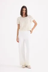 Pantalon tejido de corte recto y tiro alto, color blanco, con detalle de encaje y perlas en el ruedo.