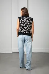 Chaleco tejido sin mangas con escote en V y cierre frontal de botones. Presenta un diseño estampado en contraste de color negro y gris, con un corte holgado y estilo oversize.