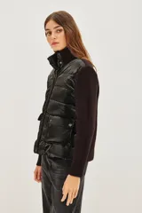 Campera híbrida de diseño moderno, con frente acolchado tipo puffer en acabado brillante y mangas tejidas en punto acanalado. Presenta cuello alto tejido y cierre frontal con botones a presión.