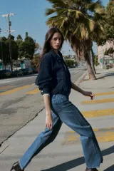 Jeans de tiro alto con diseño de cinco bolsillos, pernera recta y corte largo. Presenta cierre frontal con cremallera y botón metálico.