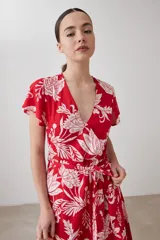 Vestido corto cruzado de color rojo con estampa floral blanca, con volados en el ruedo y lazo para ajustar en la cintura.