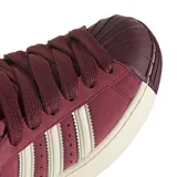 Championes Adidas Superstar II SKTR W, color bordó con detalles en blanco crema. Presentan una estructura de gamuza, las icónicas tres tiras laterales y la clásica puntera de goma reforzada.