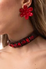 Choker de simil cuero marrón con medallones facetados de color rojo bordados a lo largo de toda la pieza. Cuenta con cadena de acero quirúrgico para ajuste.