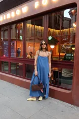Vestido largo de denim azul, de corte recto y holgado, con tirantes finos y tajo lateral en la parte inferior.
