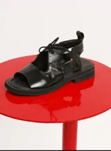 Sandalias negras de cuero charol con cordones y tira trasera.