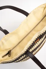 Bolso tipo tote de diseño trenzado con patrón de rayas en tonos marrones y beige, doble asa larga de material sintético oscuro y placa metálica con logo.