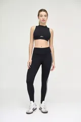 Calza deportiva negra con cintura alta y compresión media. Presenta una franja vertical blanca a lo largo de la pierna.