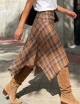 Pollera midi de corte evasé con diseño asimétrico y caída fluida. Presenta un estampado cuadrillé en tonos tierra, marrón y beige, con cintura de tiro medio.