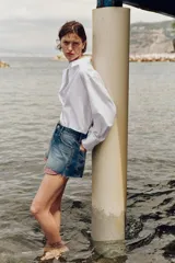 Shorts de jean tiro medio, corte mom fit, con bajo deshilachado y forro de bolsillos delanteros estampado a cuadros que asoma por debajo.