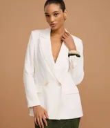 Blazer blanco de corte sastre, cruzado con doble botonadura de dos botones color beige. Presenta solapas de muesca y bolsillos de ojal con tapa en la parte delantera.