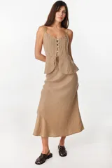 Falda larga color beige de corte sirena confeccionada en lino italiano, con pretina interior elástica y diseño fluido.