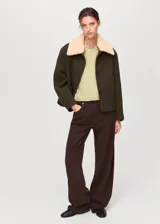 Jersey de punto fino color verde claro, con cuello redondo y manga corta. Presenta un diseño recto y un detalle de pañuelo integrado en el cuello.