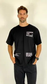 Remera negra de corte holgado con estampado tipográfico en blanco en el pecho y en la parte inferior, con cuello redondo y mangas cortas.