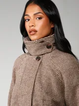 Chaqueta corta de corte recto con estampado de cuadros pequeños en tonos marrones y beige. Presenta cuello alto, mangas largas y cierre frontal oculto.