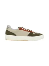 Sneaker de diseño moderno que combina cuero liso y texturado en tonos verde oliva, beige y detalles en color terracota. Presenta cordones blancos y un detalle metálico en el talón, con una suela de goma blanca de estilo plataforma.