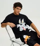 Pijama masculino de algodón con estampado de Looney Tunes, compuesto por una remera boxy fit negra con la cara de Bugs Bunny y un short negro con la cara de Pato Lucas.