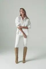 Bota de caña alta color beige, confeccionada en gamuza italiana impermeabilizada y forrada en cuero. Tiene terminación ascendente en la rodilla y taco forrado de 8,5 cm.