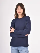 Buzo de tejido de punto color negro, con cuello redondo, mangas largas y puños anchos acanalados. Presenta un diseño con ruedo asimétrico y aberturas laterales.