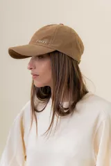 Gorra de diseño clásico con visera curva, confeccionada en material símil gamuza color bordó. Presenta un logo metálico con la palabra Peach en la parte frontal y cuenta con un sistema de ajuste posterior.