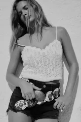 Top corto blanco con tirantes finos y escote en pico. Tejido con diseño calado de patrón geométrico y bordes festoneados.