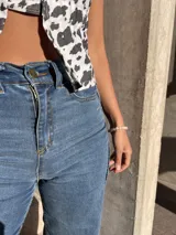 Pantalón de jean azul de corte acampanado con costuras verticales en el frente.