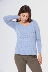 Remera de manga larga con cuello redondo, confeccionada en tejido suave con estampado de pequeñas hojas en tonos azul y rojo sobre fondo celeste.