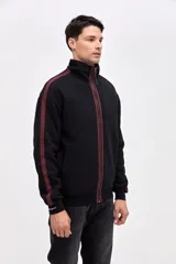 Campera de felpa con friza, de corte relajado, color negro con detalles en bordó. Presenta cuello alto, cierre frontal metálico, bolsillos laterales y cintas decorativas a contratono en las mangas.