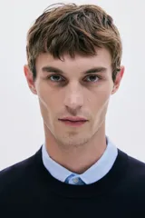 Buzo negro de punto fino con cuello redondo y remates acanalados en cuello, puños y bajo. Presenta un corte estándar para una silueta clásica y cómoda.