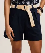 Short recto de cintura alta color crudo, confeccionado en viscolino, con trabillas en la cintura, pliegues y cierre tradicional. Incluye cinturón de rafia artificial con hebillas de argollas.