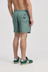 Short de baño azul, de corte clásico y largo corto, con cintura elástica y cordón ajustable bicolor. Cuenta con bolsillos laterales y uno trasero.