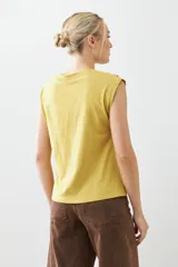 Remera color pistacho con cuello en V y botones decorativos en los hombros.