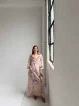 Vestido largo rosado con estampado floral en tonos marrones y beige, cuello drapeado y mangas largas holgadas.