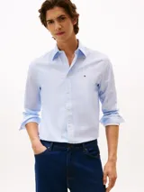 Camisa de manga larga color celeste claro con microestampado de puntos blancos. Presenta cuello con botones, cierre frontal de botones y el logo de Tommy Hilfiger bordado en el pecho.