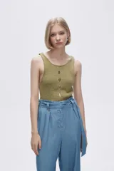 Musculosa verde melange de tejido de punto con tres aberturas circulares en el frente.