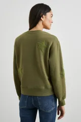 Buzo verde militar de algodón con cuello redondo y mangas largas. Tiene apliques de estrellas en el frente y en las mangas.