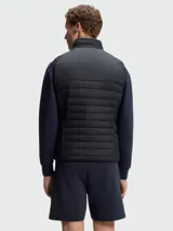 Chaleco acolchado Boss modelo Urbanex, color negro, con cierre frontal completo, cuello alto y diseño híbrido con paneles horizontales en la parte superior.