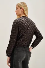 Campera acolchada de diseño matelasse, color negro, con cuello redondo, cierre frontal y puños elásticos a rayas.
