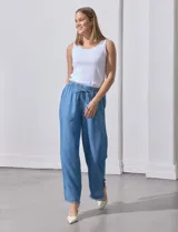 Pantalón celeste de lyocell, corte ancho, con pretina elastizada con lazo de ajuste, bolsillos verticales y ruedo desflecado.