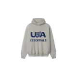 Hoodie de corte oversize en color gris claro, con capucha y bolsillo canguro. Presenta un estampado frontal en azul marino con el texto "USA" y "ESSENTIALS" debajo.